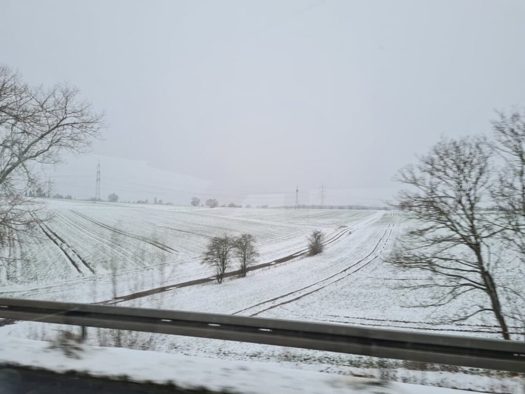 eine verschneite Winterlandschaft aus dem Autofenster